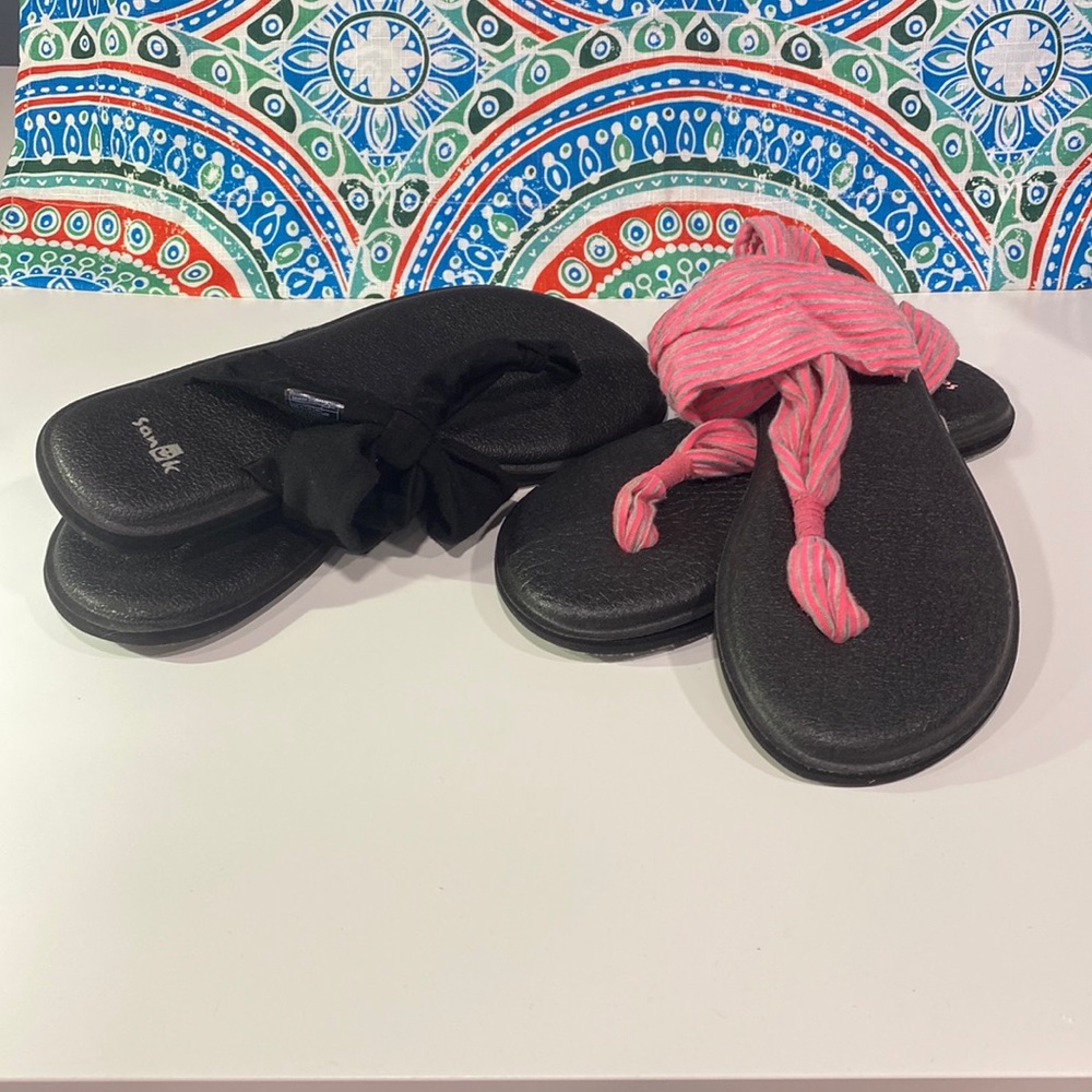 2 pair of Sanuk straps sandals. Woman’s size 7.  One black and one pink.